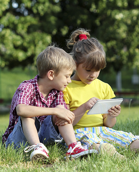 little girl and boy with tablet in park